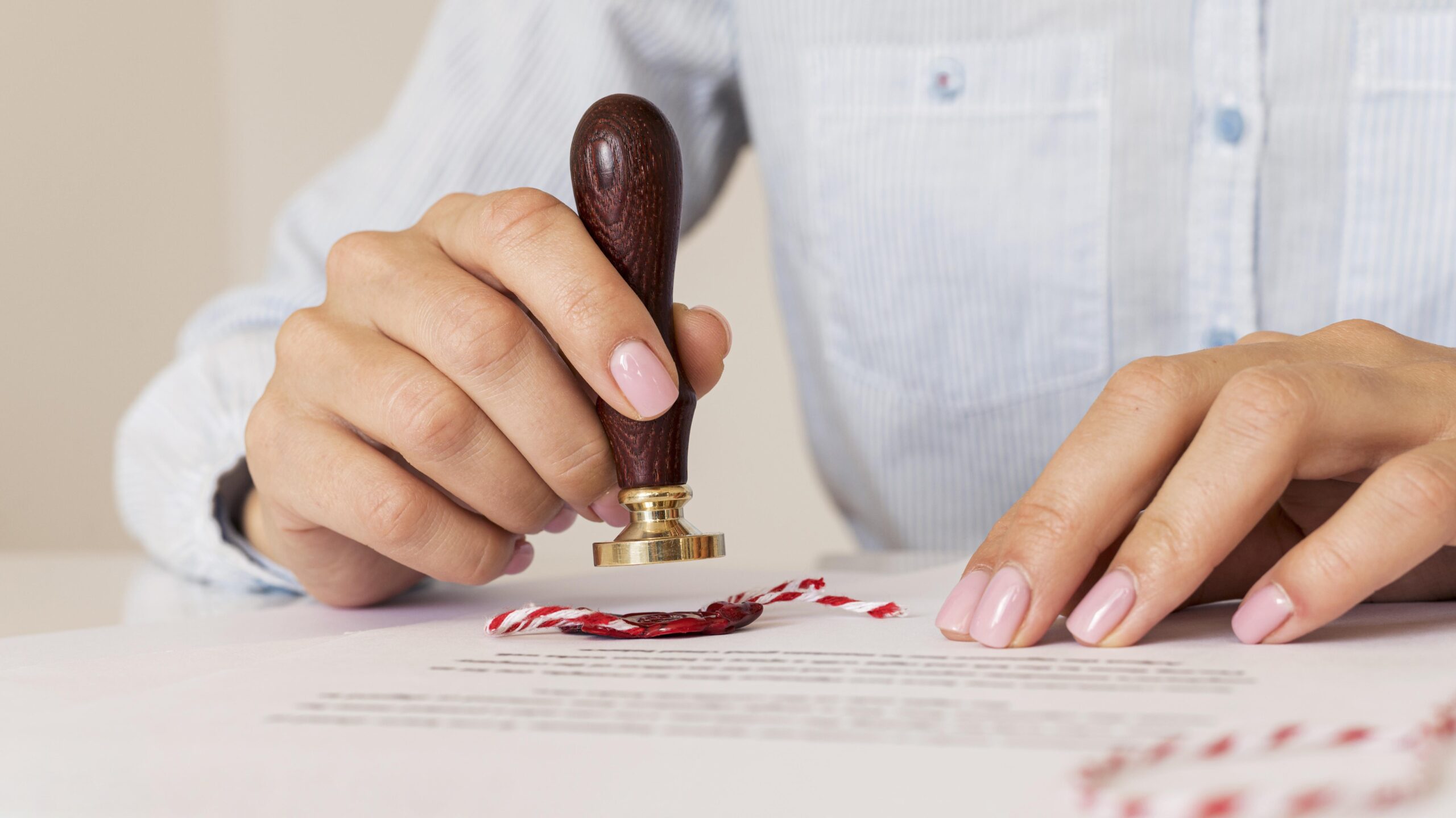 person-using-wax-seal-blurred-certificate